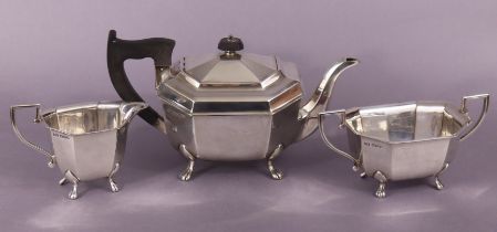 A George VI silver three-piece tea service of eight-sided oblong shape, each on four paw feet;