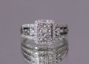 A diamond cluster ring, the central pave-set rectangular panel within a border of small round-cut