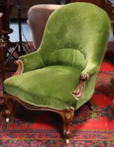A Victorian walnut nursing chair with padded seat, back & arms upholstered green velour, with carved