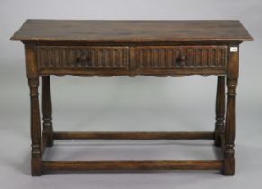 A reproduction oak serving table with a rectangular top, fitted two frieze drawers with moulded