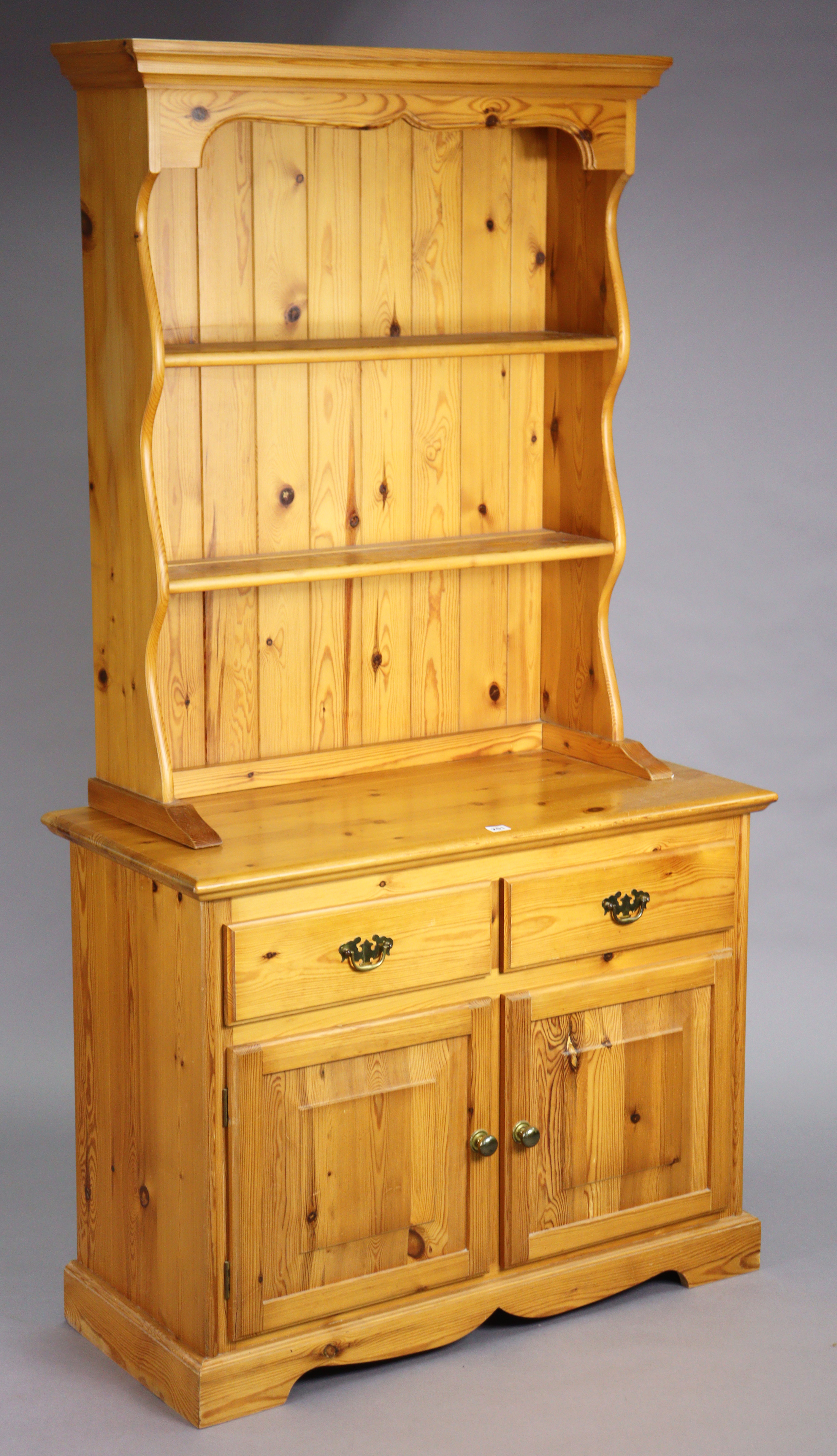 A pine small dresser the upper part with two open shelves & having a panelled base, the base