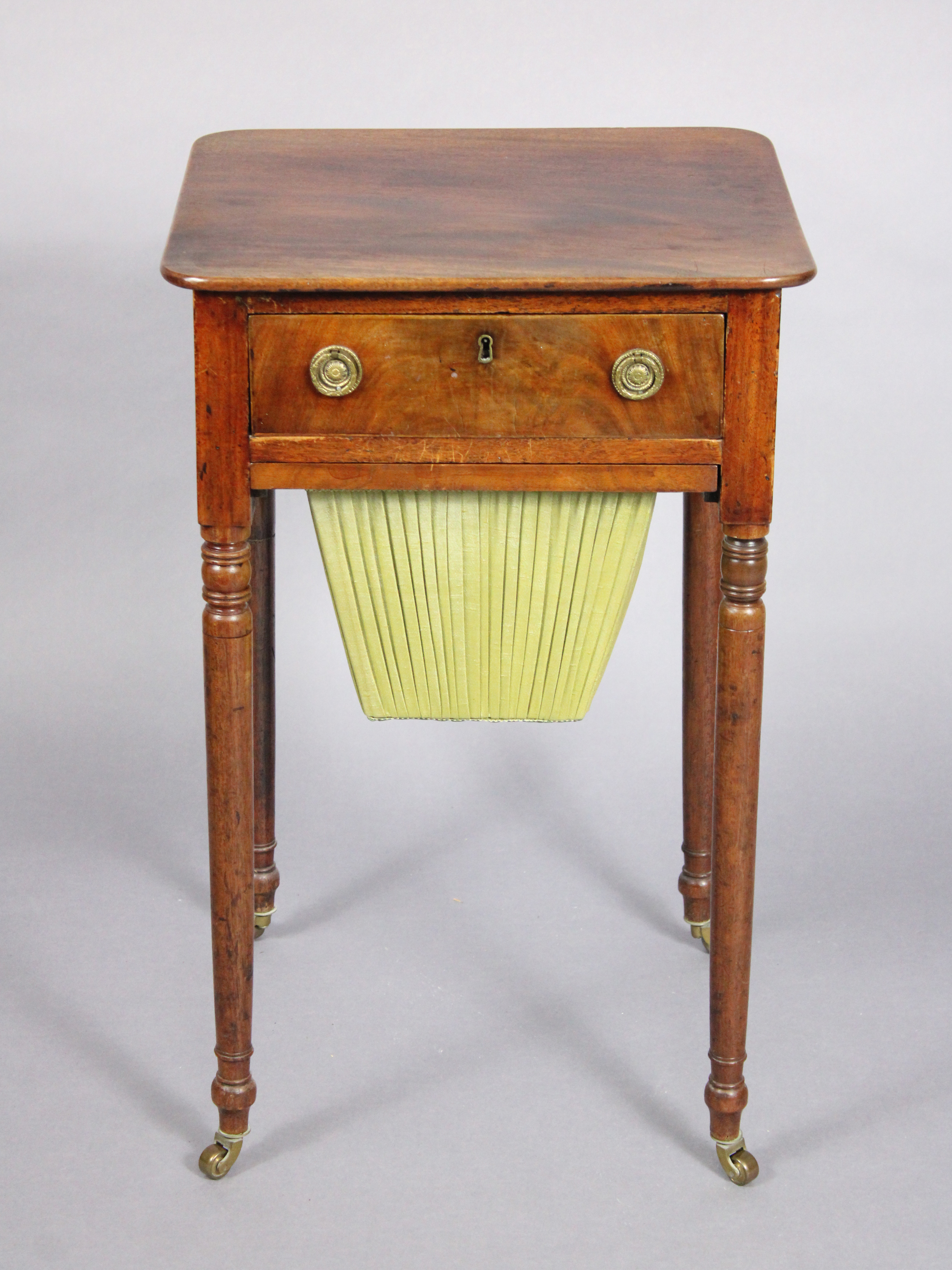 A late Georgian mahogany needlework table fitted frieze drawer with brass ring handles above a