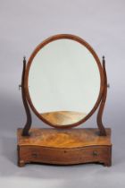 A Georgian mahogany oval swing dressing mirror on shaped supports & serpentine-front box base fitted