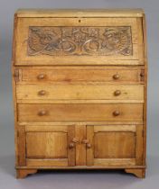 An oak bureau with a fitted interior enclosed by a carved fall-front above three long drawers and