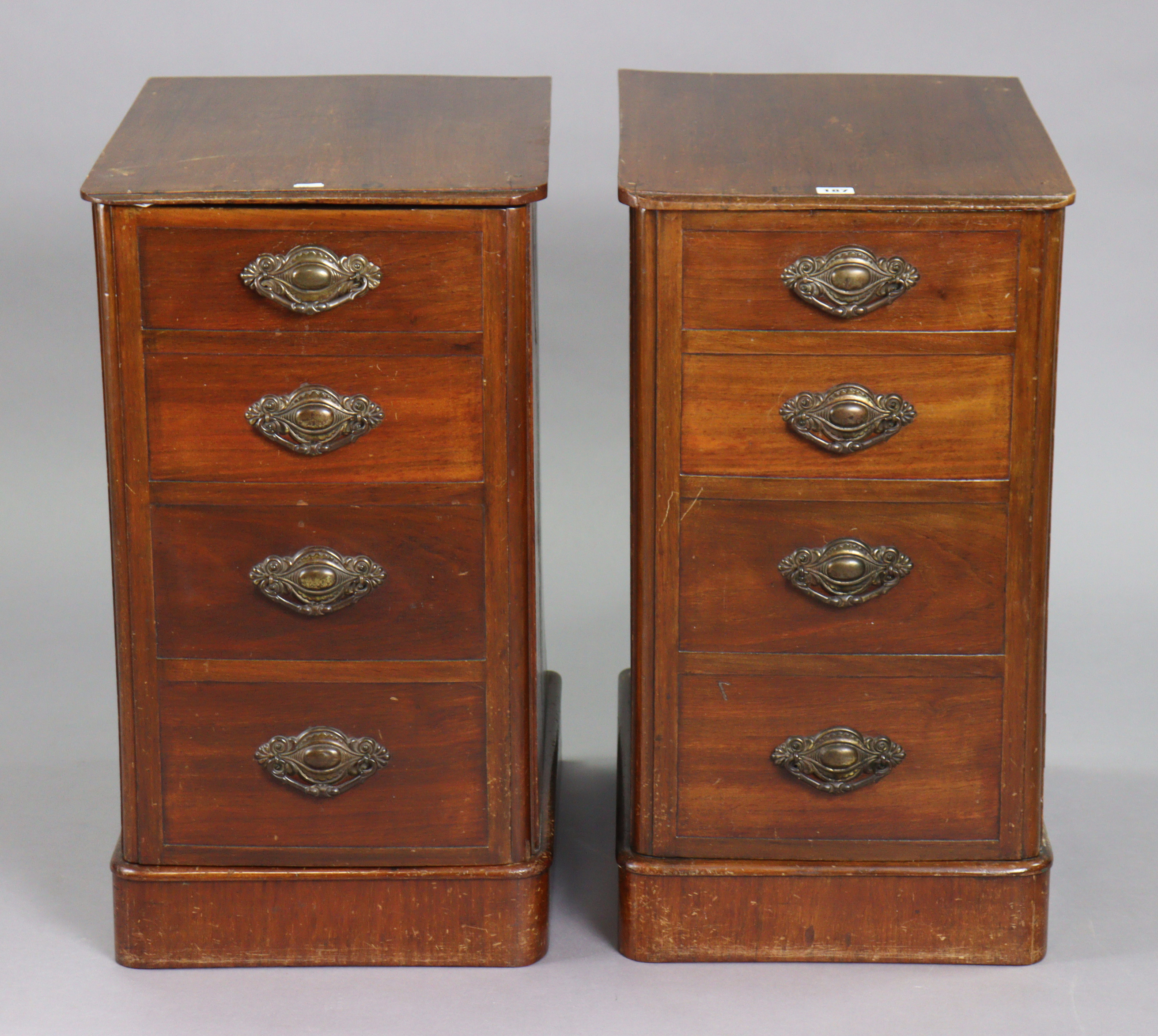 A pair of mahogany bedside chests each fitted four long graduated drawers with cast-iron swing