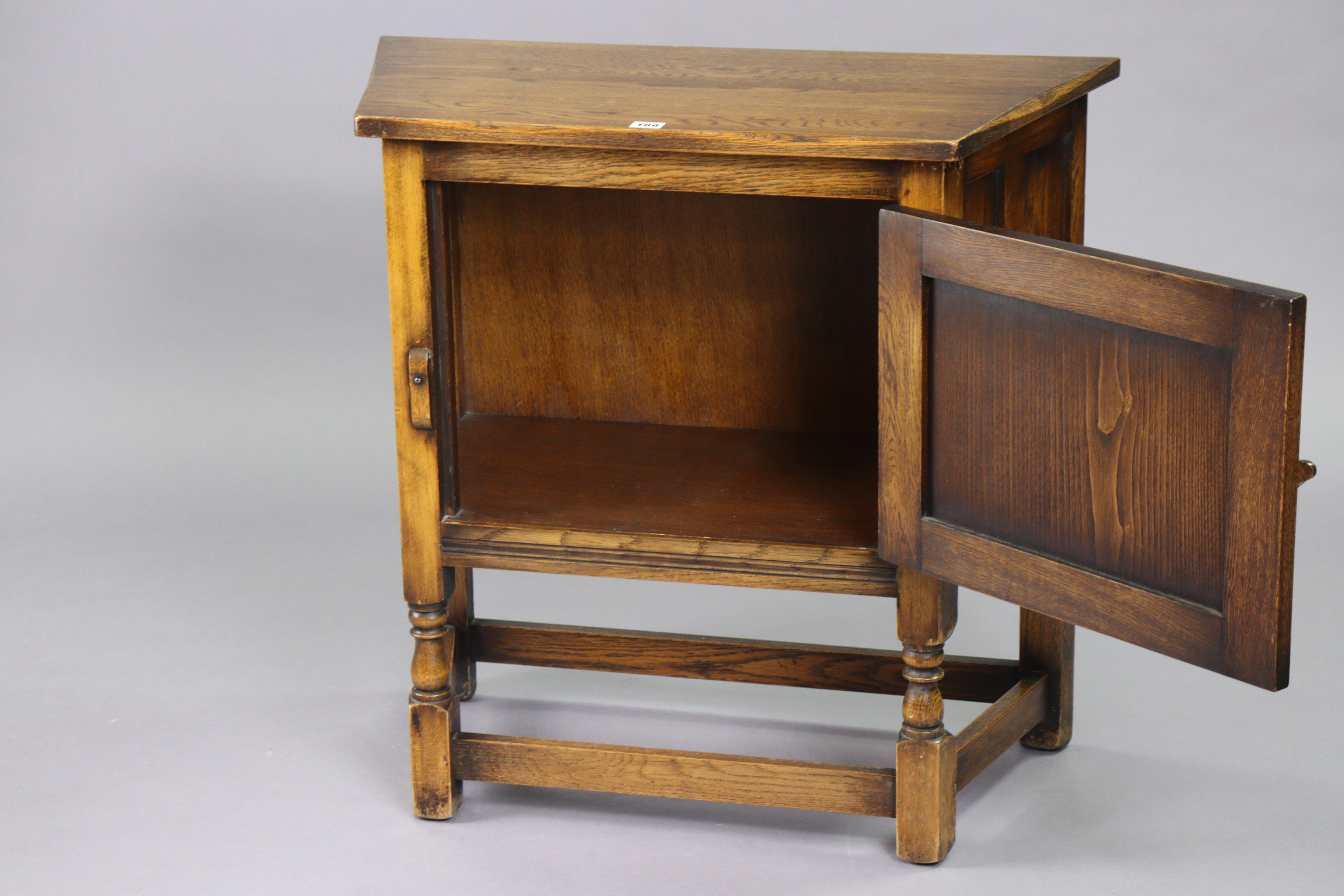 A small oak side cabinet with canted sides, enclosed by a carved panel door, & on turned supports - Image 2 of 3