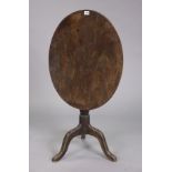 A 19th century mahogany tripod table with an oval tilt-top, & on a vase-turned centre column & three
