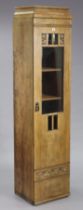 An oak tall standing narrow cabinet having four adjustable shelves enclosed by a bevelled glass &