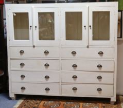 A 20th century white painted wooden haberdasher’s cabinet enclosed by two pairs of glazed