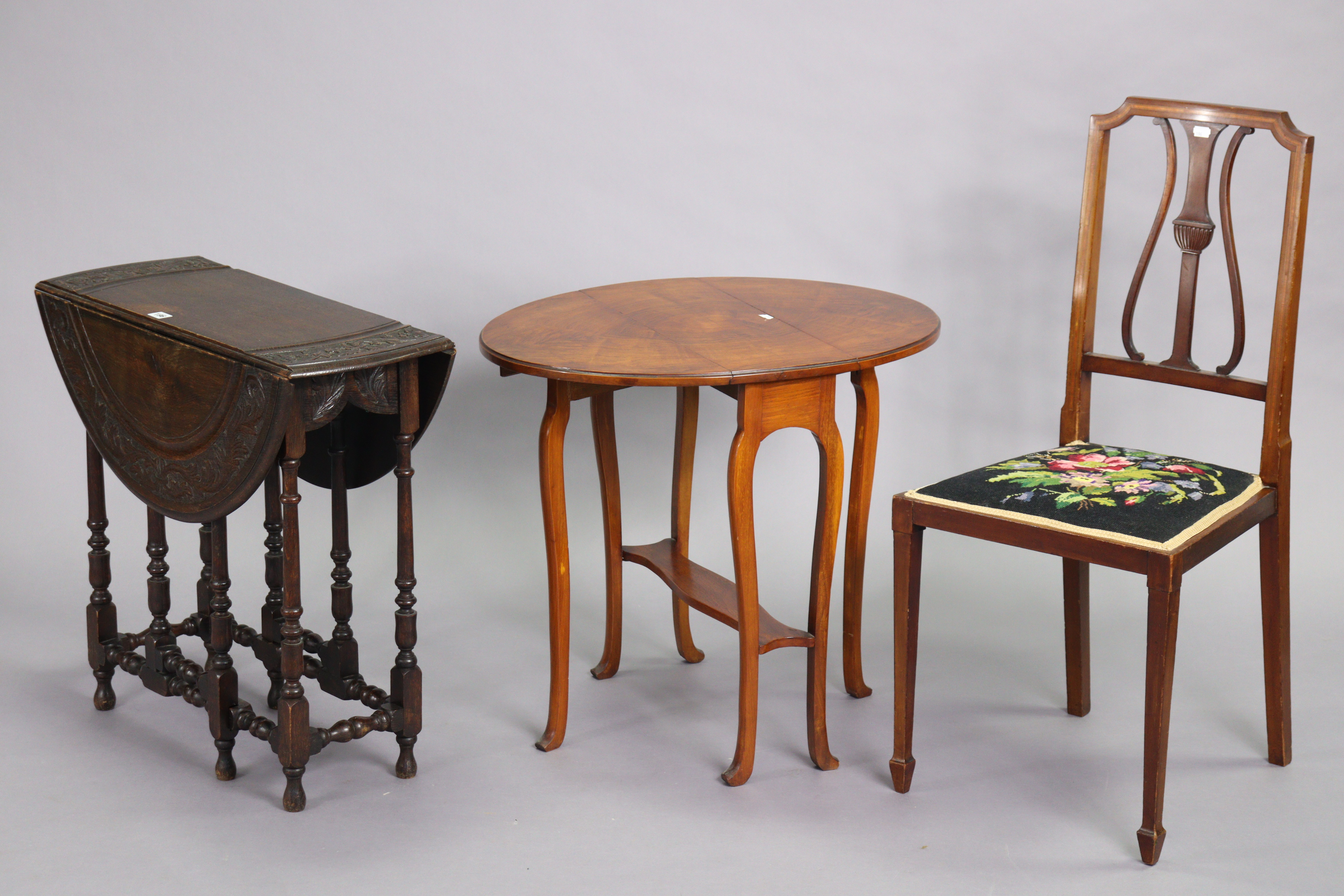 An early 20th century oak oval drop-leaf occasional table with a carved foliate border, & on