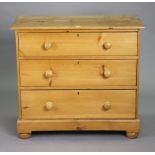 A pine small chest fitted three long graduated drawers with turned knob handles, & on a plinth