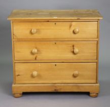 A pine small chest fitted three long graduated drawers with turned knob handles, & on a plinth