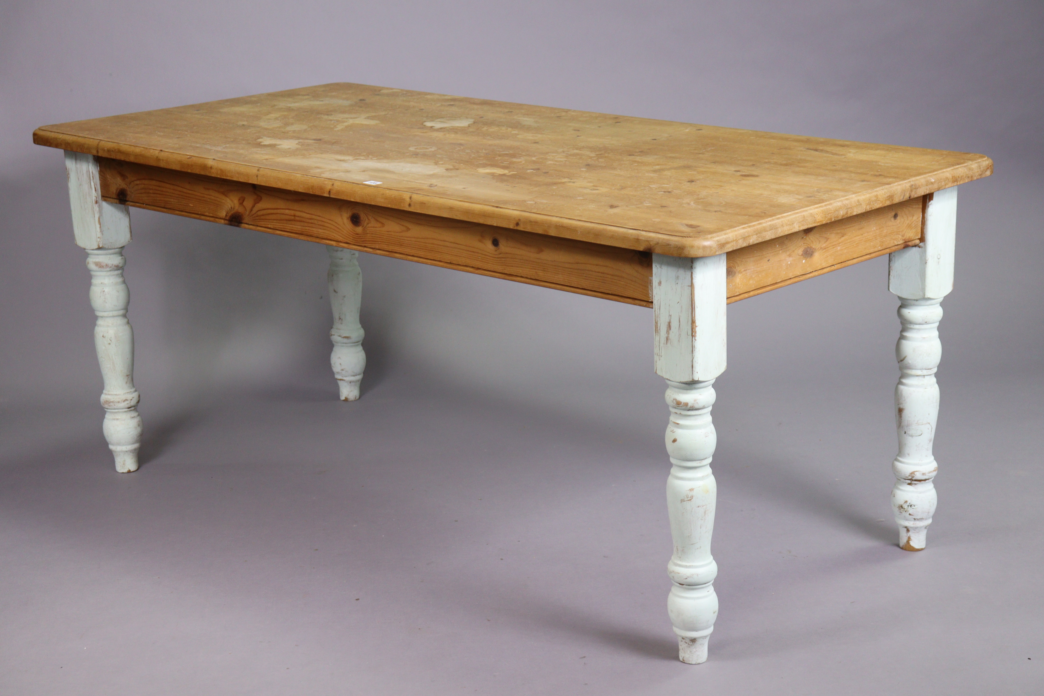 A pine kitchen table with a moulded edge & rounded corners to the rectangular top, & on four painted
