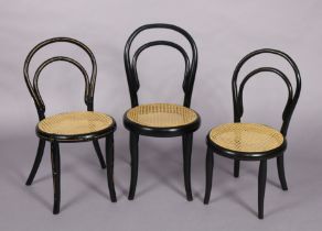 A Thonet ebonised child’s chair with gold painted decoration & cane circular seat, & two similar