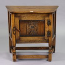A small oak side cabinet with canted sides, enclosed by a carved panel door, & on turned supports