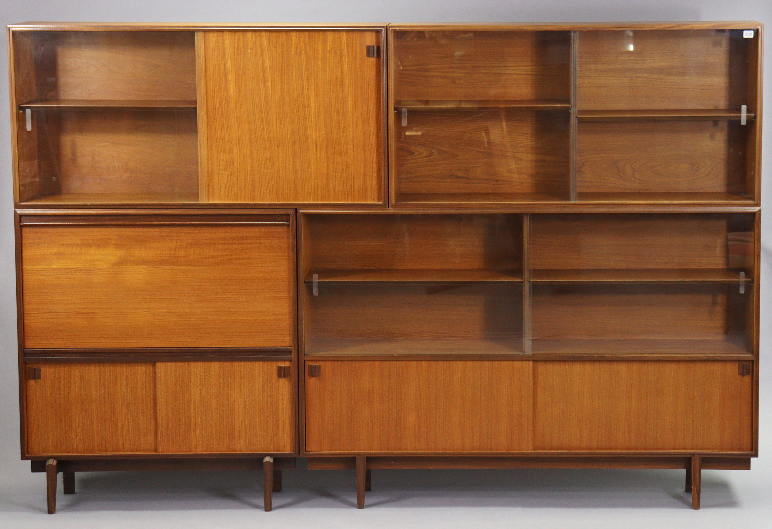 A mid-20th century teak tall wall unit fitted with an arrangement of shelves & cupboards, & on short