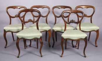 A set of six mid-Victorian rosewood dining chairs with carved rounded open backs, padded seats, & on