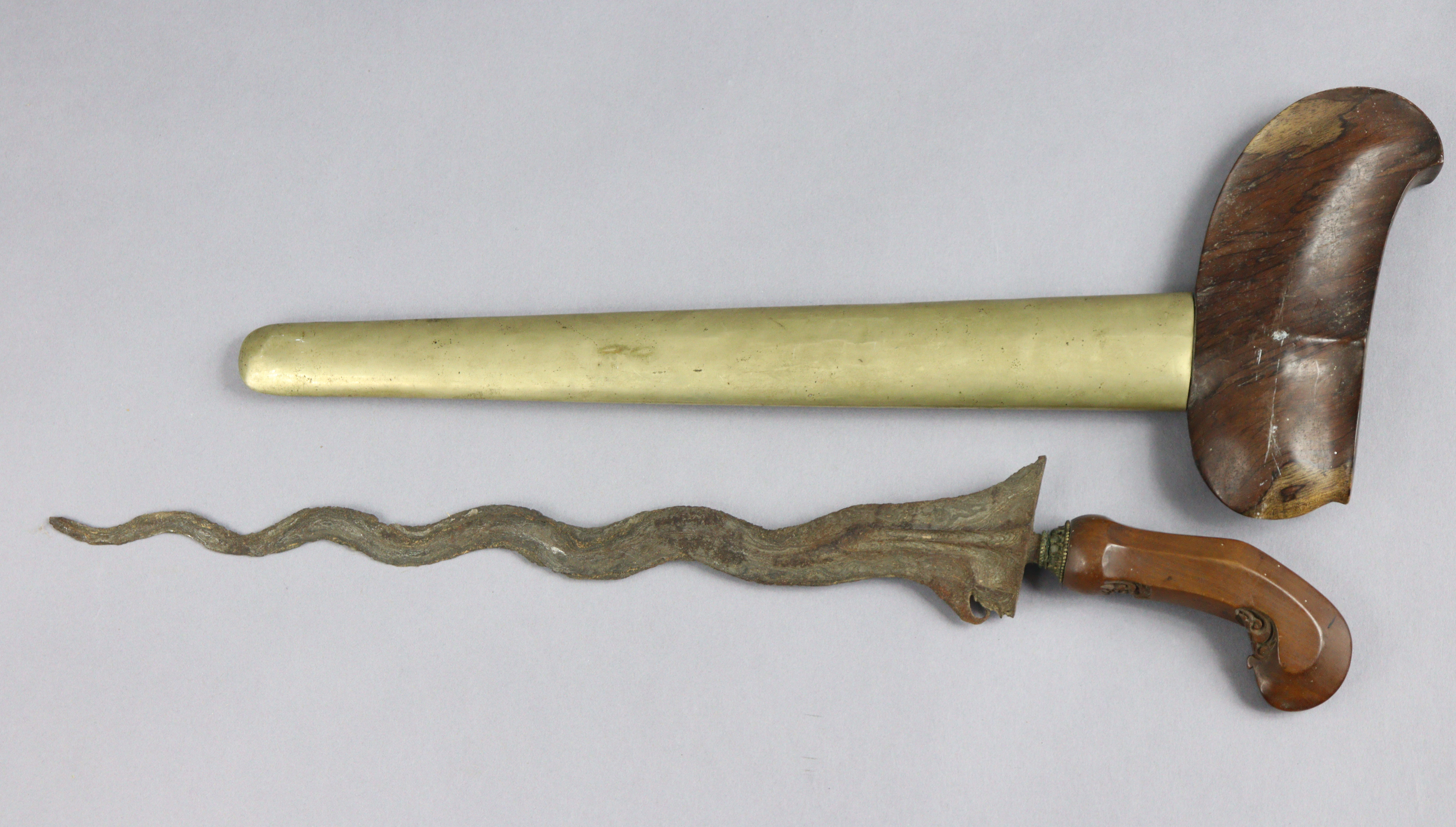 An Indonesian Kris having a 33.5cm long wavy blade, carved wooden grip, & with a metal-covered