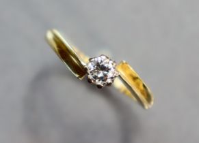 A yellow metal cross-over ring set single diamond; size: P; 2 gm.