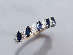 A 9ct. gold ring set row of five oval-cut sapphires with pairs of small white stones in between;