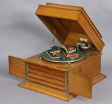 A vintage oak-cased table-top gramophone enclosed by a hinged lift-top, & a pair of panel doors,
