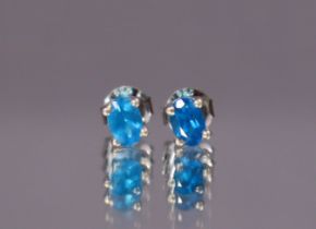 A pair of neon-blue apatite ear-studs, the oval-cut stones set to un-marked white metal mounts. (1.