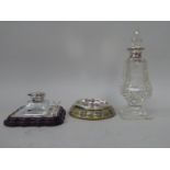 A glass inkwell with a silver collar and hinged lid, set in a silver mounted stand, incorporating