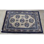 A Chinese washed woollen rug, decorated with six Oriental motifs, on a blue and cream coloured