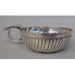 An antique white metal wine taster, the bowl with embossed and incised decoration and a tab top ring