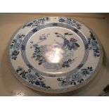 An 18thC Dutch Delft charger, decorated in blue and white Chinese style with flora, insects and