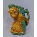 A late Victorian majolica novelty jug, decorated in tones of brown and green with a monkey holding