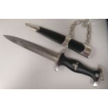 A German SS dagger with emblems and a moulded handgrip, the 8.25"L blade bears a motto, in a sheath,