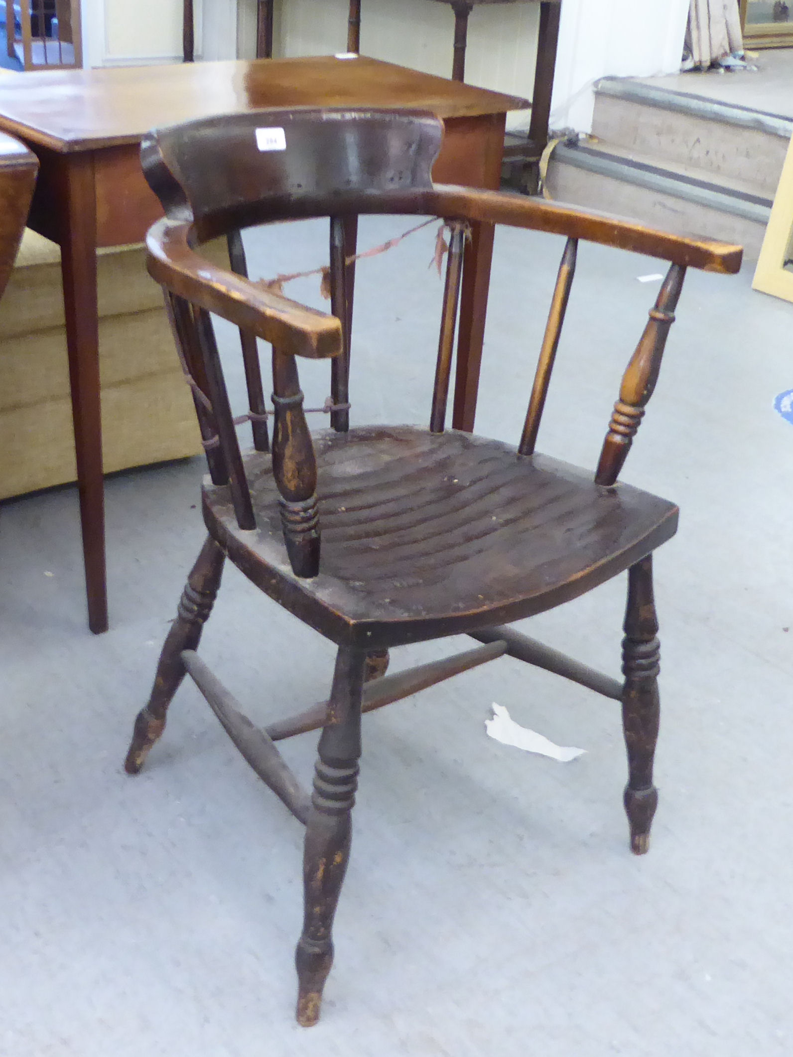 An early 20thC stained beech framed captain's chair with a spindled back and solid seat, raised on