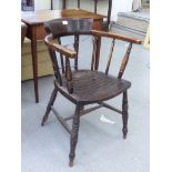 An early 20thC stained beech framed captain's chair with a spindled back and solid seat, raised on