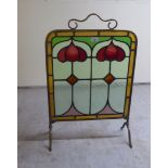An early 20thC Art Nouveau inspired, brass framed, stainless glass firescreen, raised on splayed