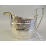 A George III silver oval cream jug with scratch and bright-cut engraved decoration and a high loop