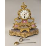 A late 19thC French gilt metal cased mantel timepiece with a painted porcelain plaque, on a separate