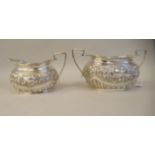 An Edwardian silver twin handled sugar bowl of oval, ogee form with demi-reeded floral and foliate