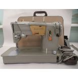 A vintage electric Singer sewing machine, in a hard travel case