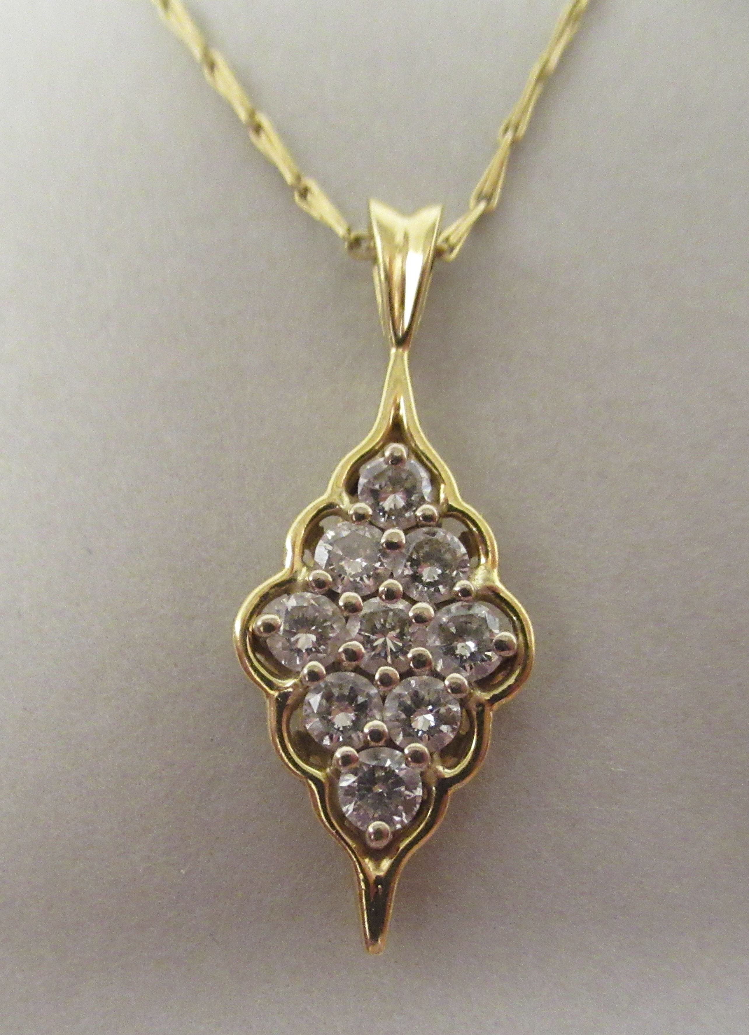 A gold coloured metal nine stone set diamond pendant, on a fine twist wire link neckchain and ring