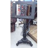 A Victorian style dark stained carved softwood music stand with a height adjustable stem, elevated