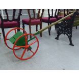 An early 20thC red and green painted steel seed spreader, on a wooden handle  70"L