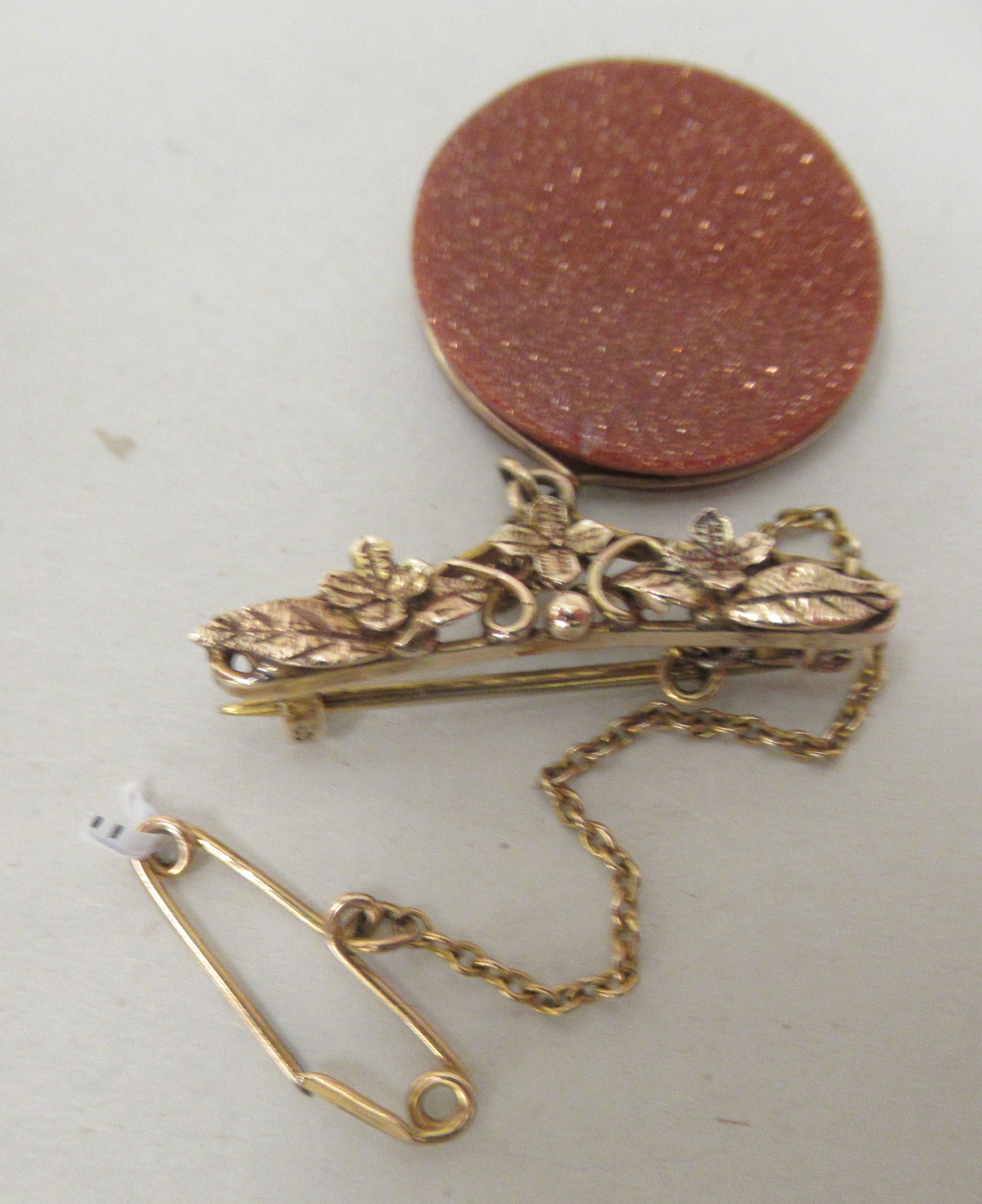 A yellow metal brooch with a gold stone pendant