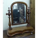 A late Victorian toilet mirror, the arched plate set in a mahogany frame, pivoting on ring turned