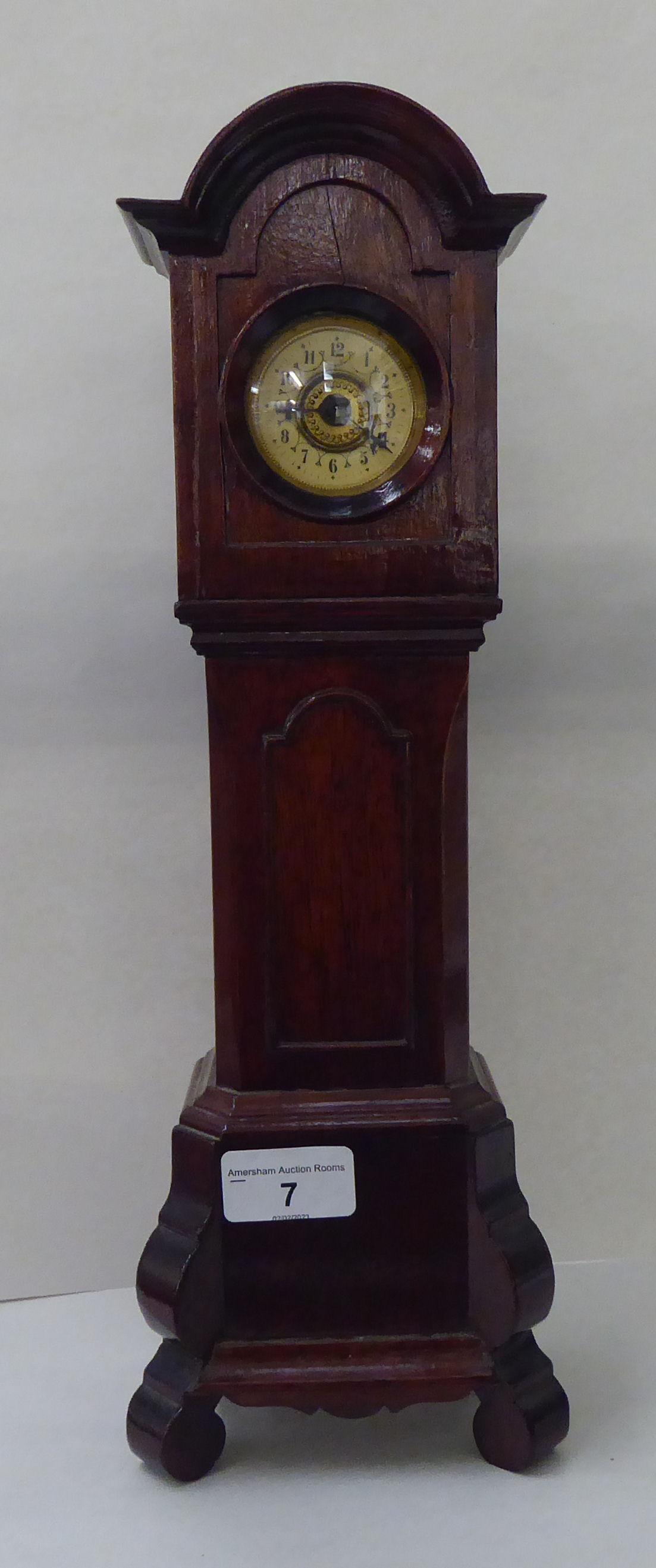 An early 20thC mahogany mantel timepiece, fashioned as a longcase clock with an arched hood and