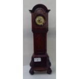 An early 20thC mahogany mantel timepiece, fashioned as a longcase clock with an arched hood and