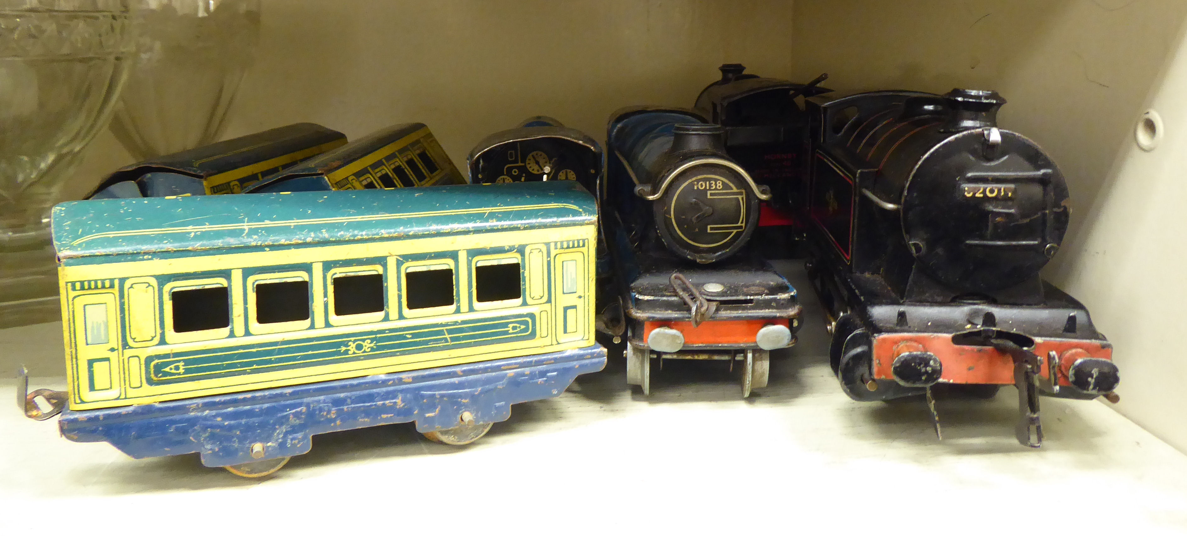 Four 0 gauge, tinplate clockwork model railway locomotives and three matching passenger coaches