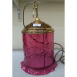 A modern brass framed hanging lamp with a cranberry glass shade  14"h