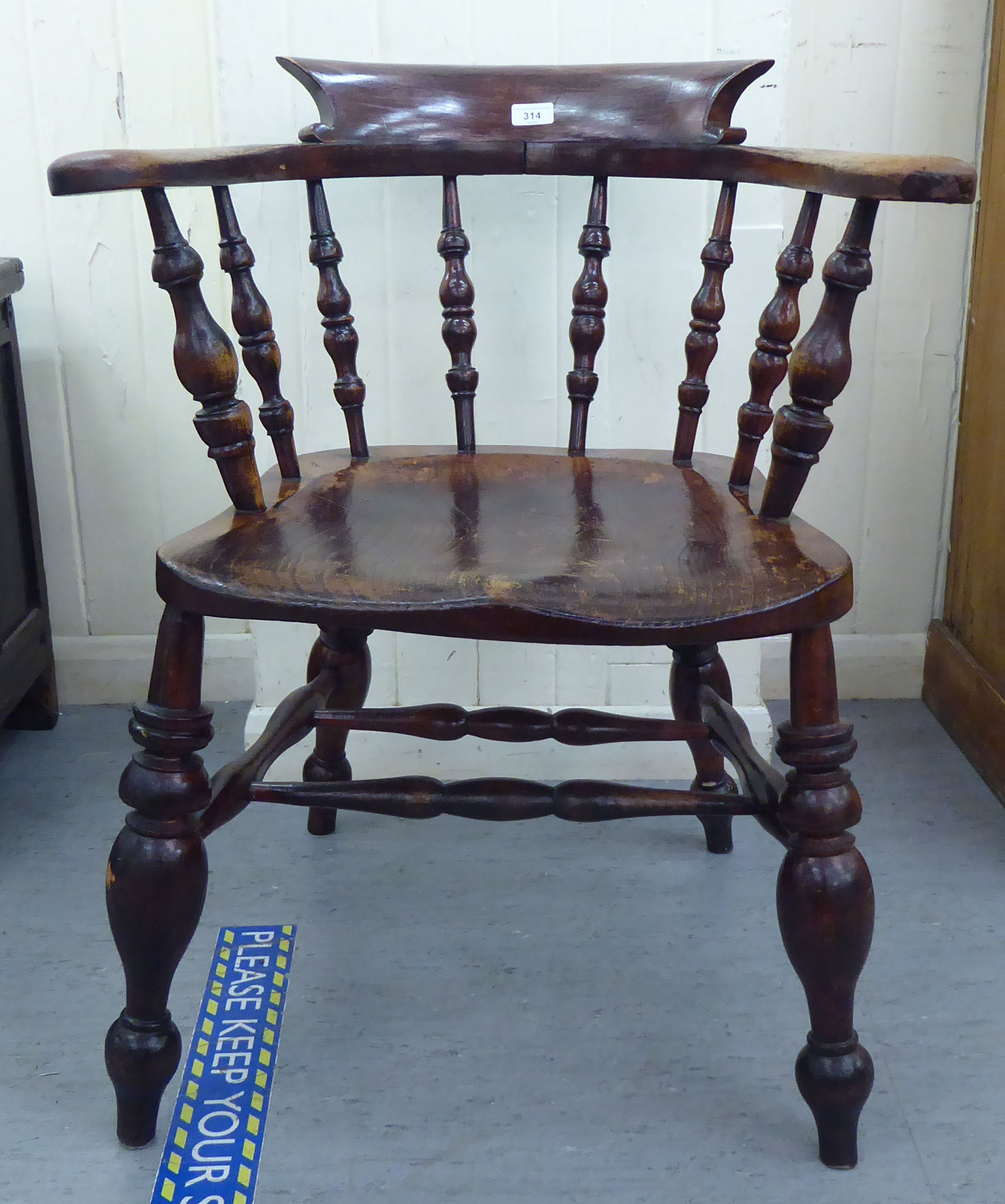 A late 19thC stained beech and elm framed Captains chair, the round back with scrolled level arms,