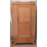 An early 20thC pine wardrobe with a central panelled door, over a base drawer, raised on bracket